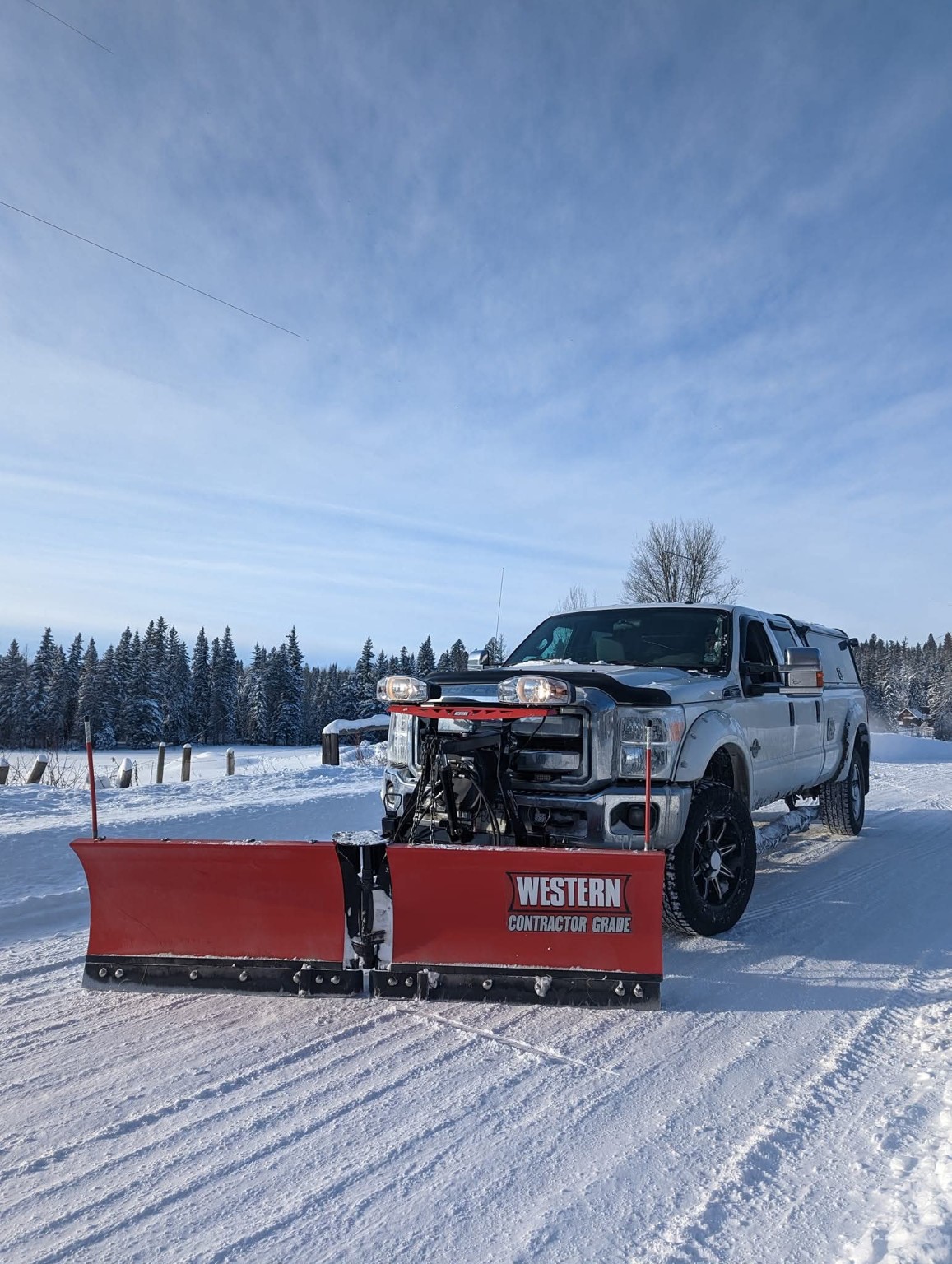 Cariboo Contracting truck equipped with a snow plow on a snowy property